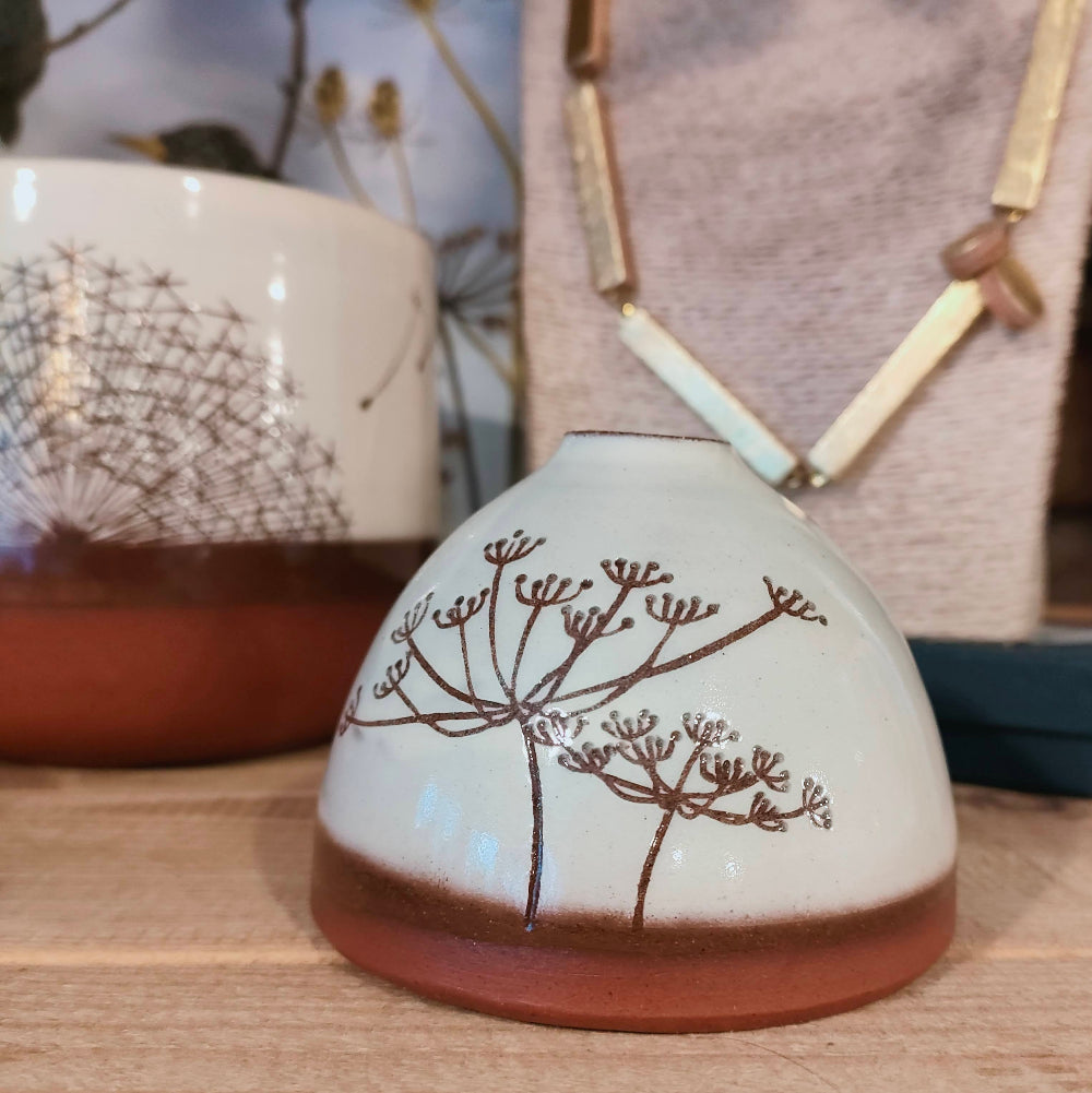 Ceramic vase with brown cow parsley design on a wooden surface
