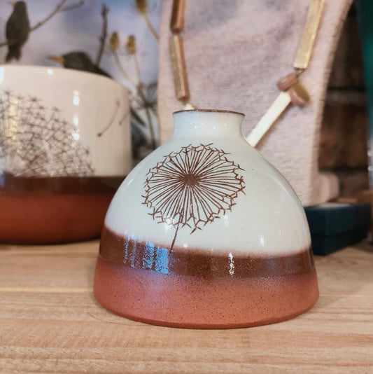 Ceramic vase with dandelion design on a wooden surface