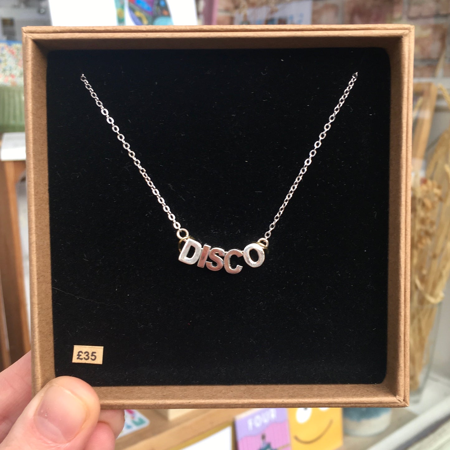 Three variations of a disco necklace with matt gold plated letters on adjustable chains.