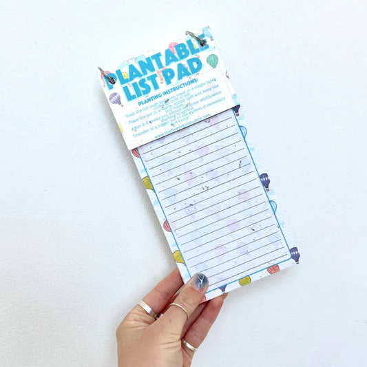 Hand holding a plantable list pad with a white background