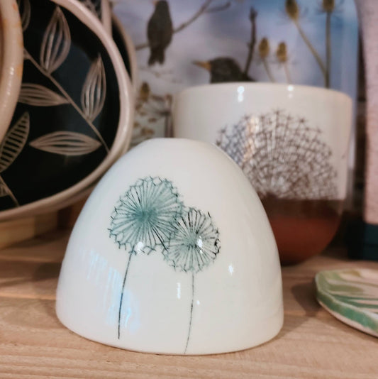 Ceramic bud vase with dandelion design on a wooden surface