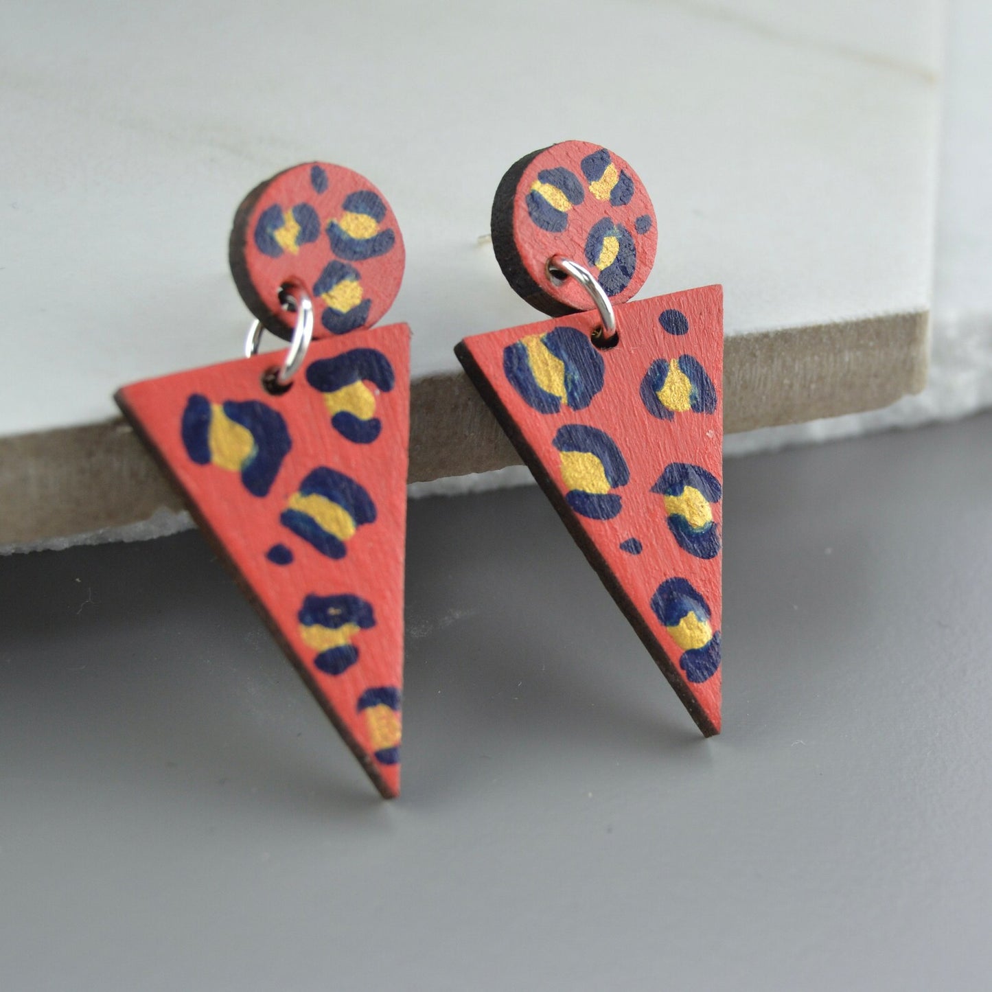 Triangular earrings with a colorful pattern on a gray surface